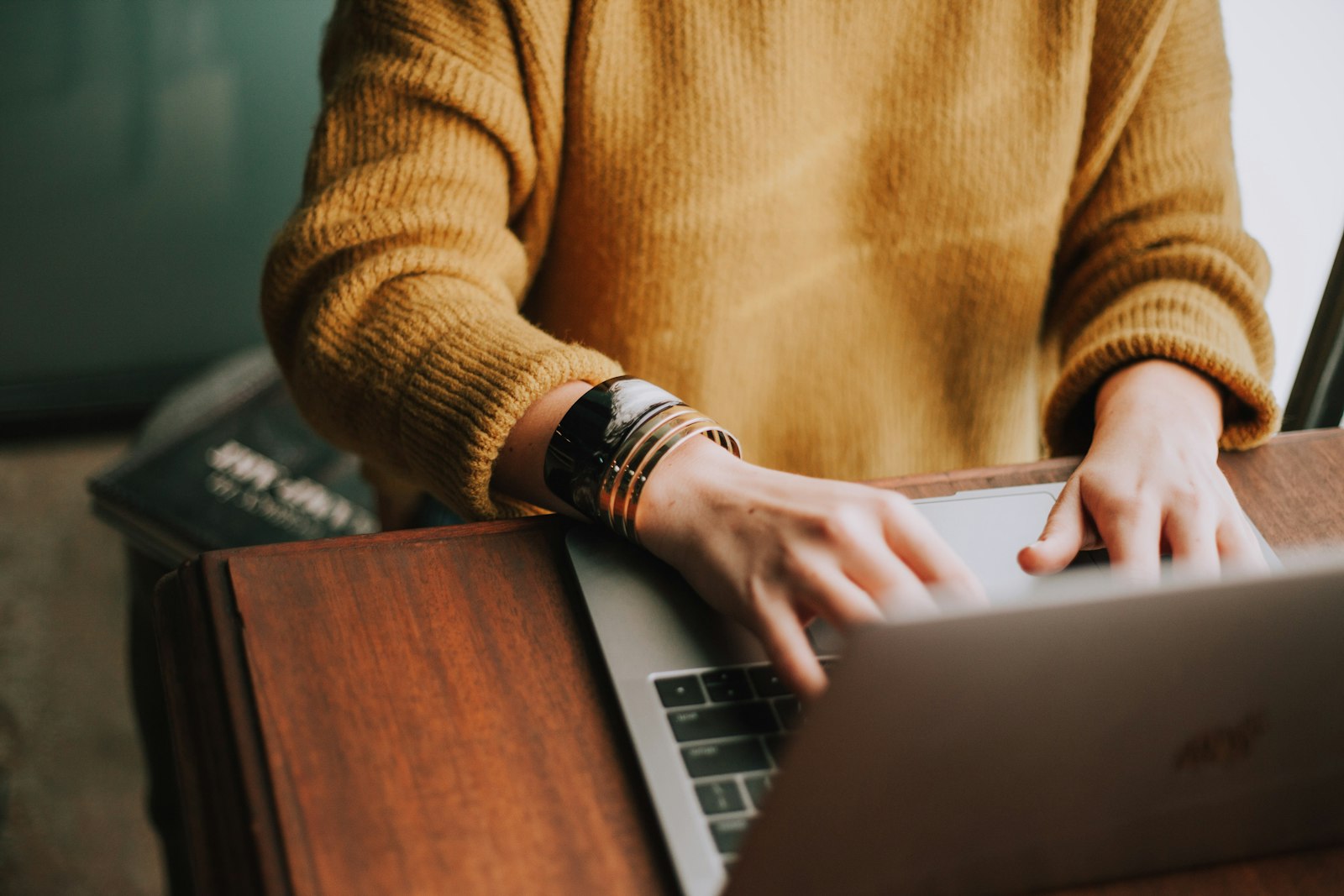 Hands typing on a laptop at a wooden desk