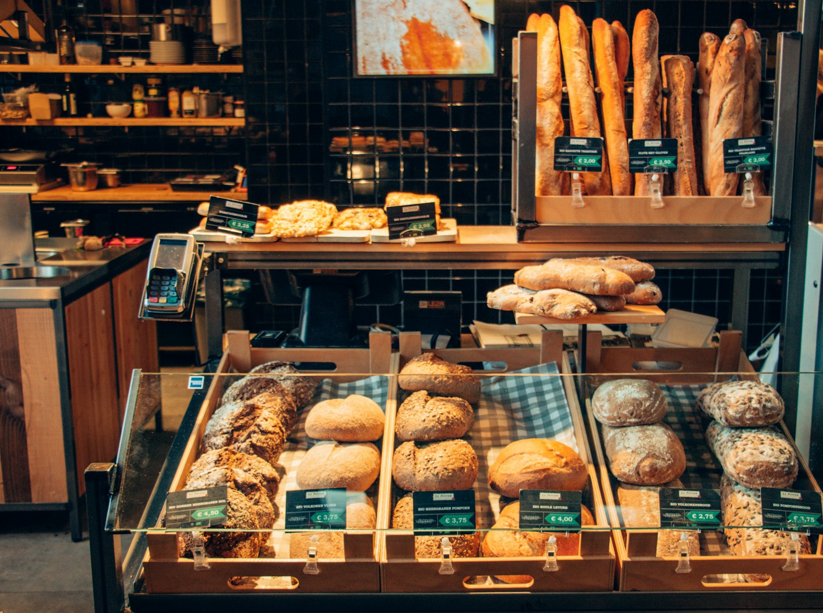 A warm, wood-lined bakery display case stocked with fresh bread and pastries