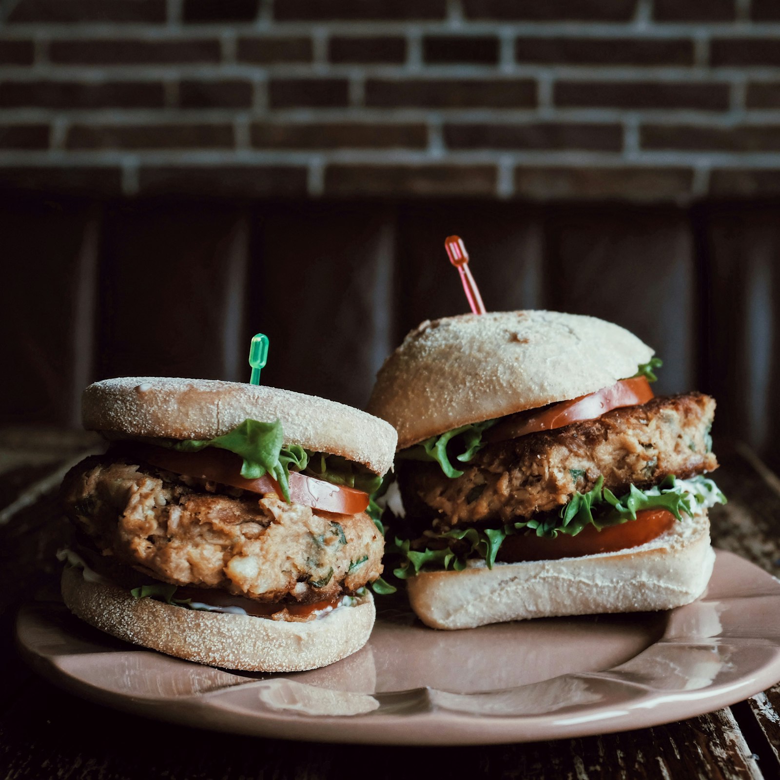 Sliders plated on a table against a dark brick background