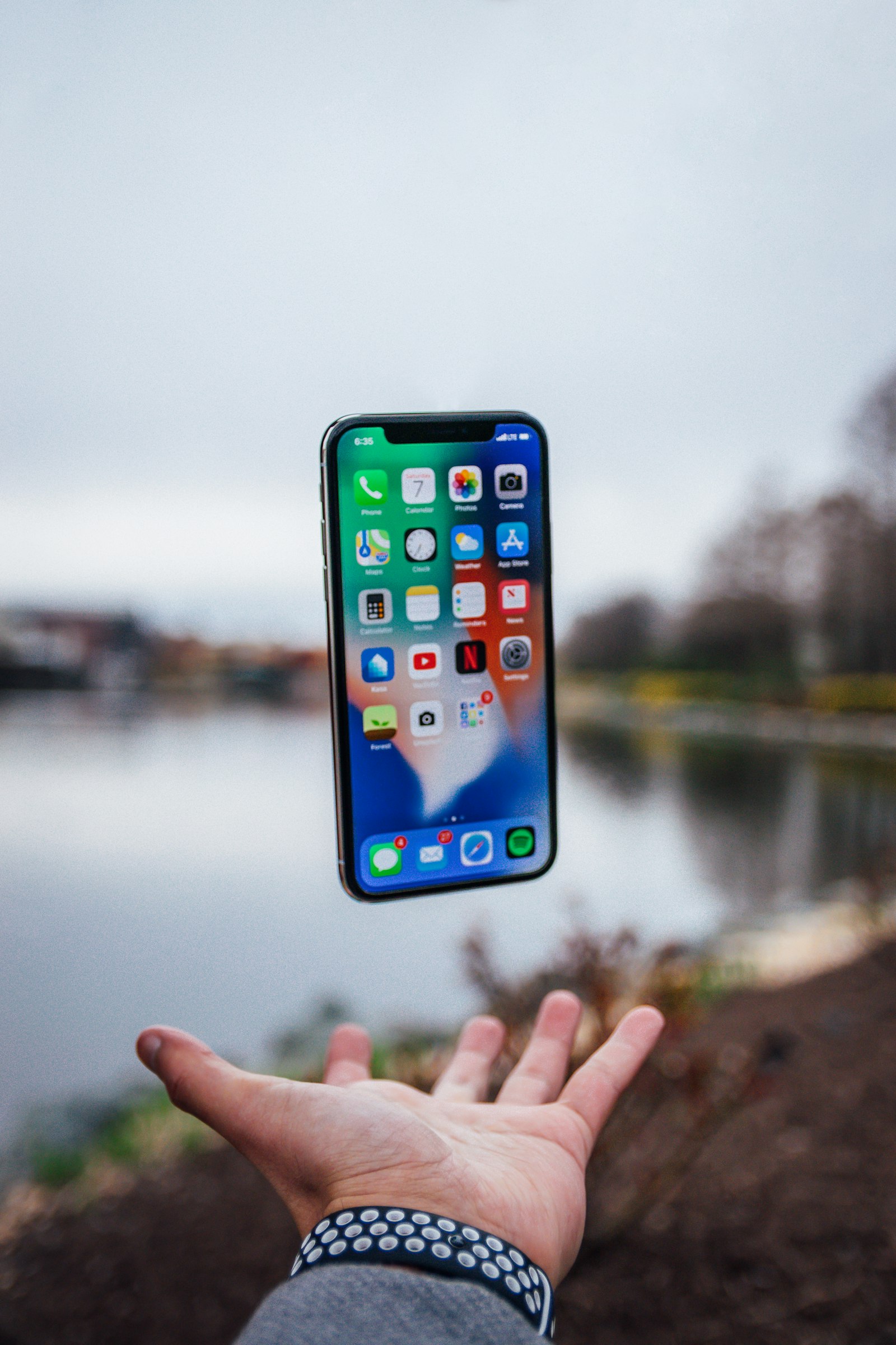 A phone held out against a blurred waterside background